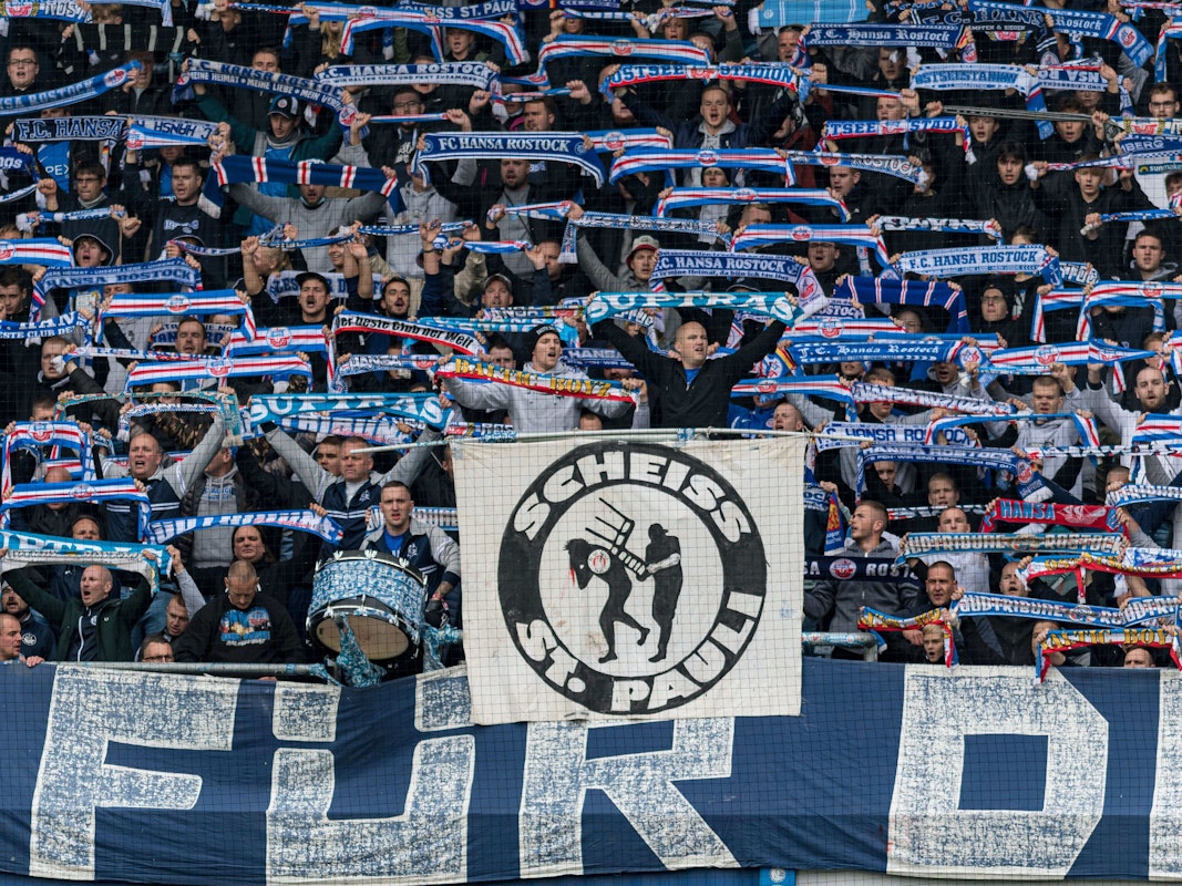 Fans von Hansa Rostock halten ein Banner gegen den FC St. Pauli hoch.