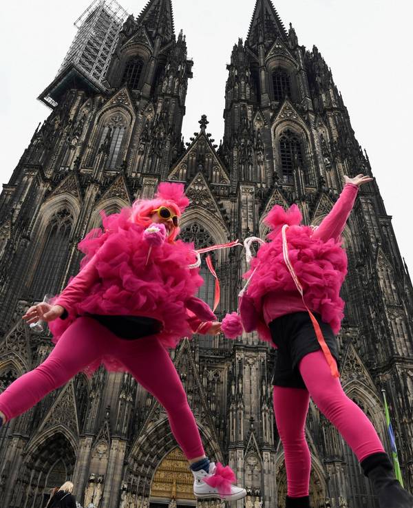 Verkleidete Frauen springen vor dem Kölner Dom in die Höhe. Die Weiberfastnacht leitet den Beginn des Straßenkarnevals ein.