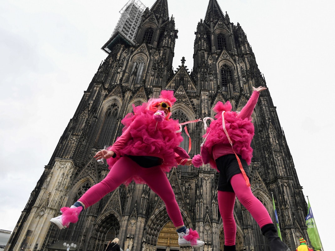Verkleidete Frauen springen vor dem Kölner Dom in die Höhe. Die Weiberfastnacht leitet den Beginn des Straßenkarnevals ein. +++ dpa-Bildfunk +++