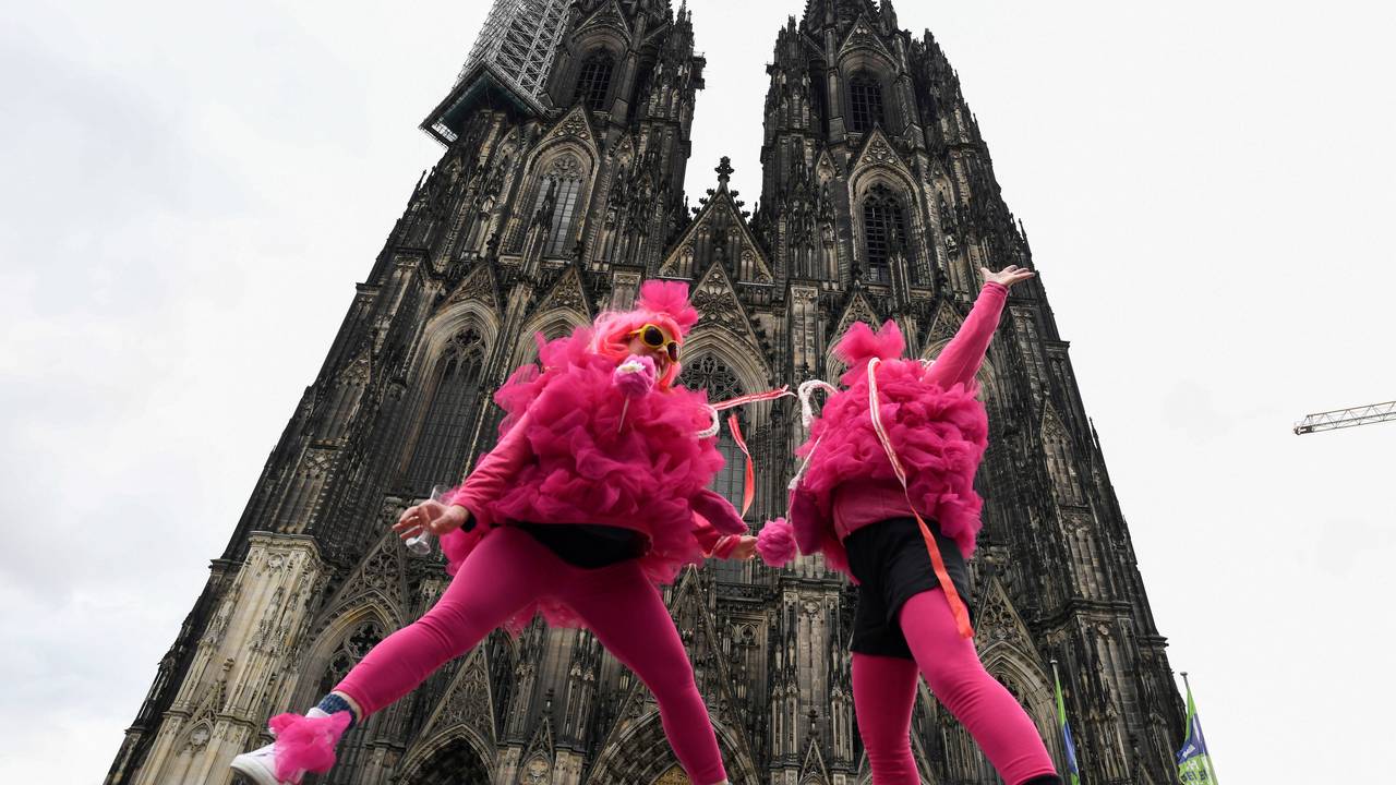 Verkleidete Frauen springen vor dem Kölner Dom in die Höhe. Die Weiberfastnacht leitet den Beginn des Straßenkarnevals ein.