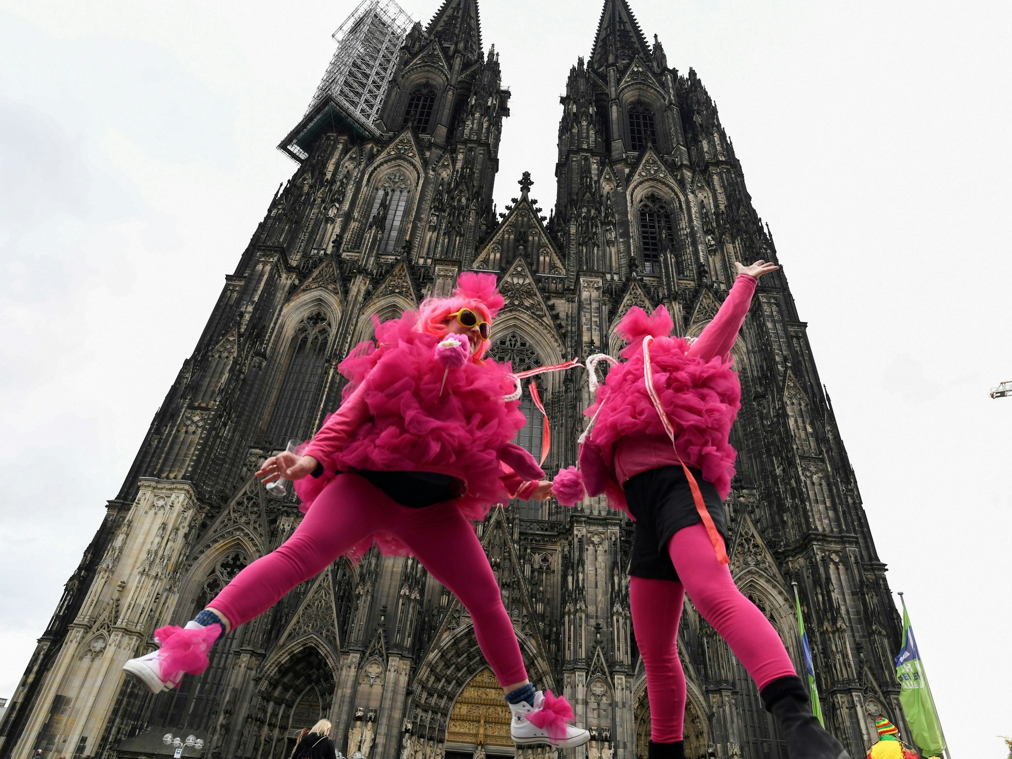 Verkleidete Frauen springen vor dem Kölner Dom in die Höhe. Die Weiberfastnacht leitet den Beginn des Straßenkarnevals ein.
