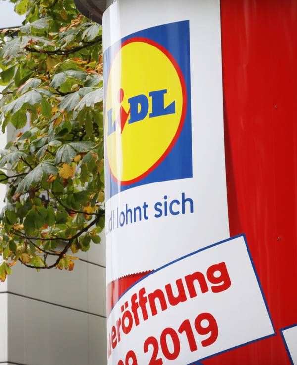 Auf einer Litfaßsäule prangt eine Lidl-Werbung, im Hintergrund ist eine Aldi-Filiale zu sehen.