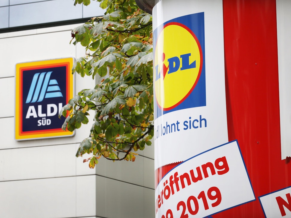 Auf einer Litfaßsäule prangt eine Lidl-Werbung, im Hintergrund ist eine Aldi-Filiale zu sehen.