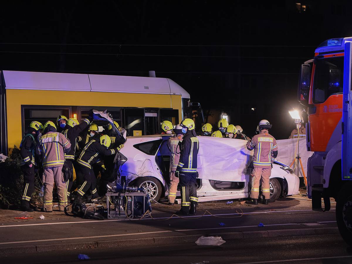 Einsatzkräfte halten am frühen Sonntagmorgen neben einer Straßenbahn an der Liebenwalder Straße / Landsberger Allee in Lichtenberg ein Tuch als Sichtschutz bei der Bergung einer Leiche.