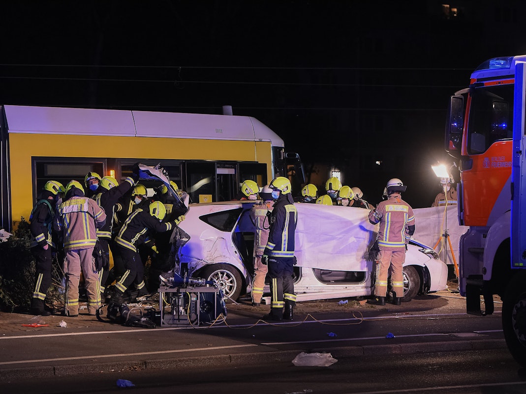 Einsatzkräfte halten am frühen Sonntagmorgen neben einer Straßenbahn an der Liebenwalder Straße / Landsberger Allee in Lichtenberg ein Tuch als Sichtschutz bei der Bergung einer Leiche.