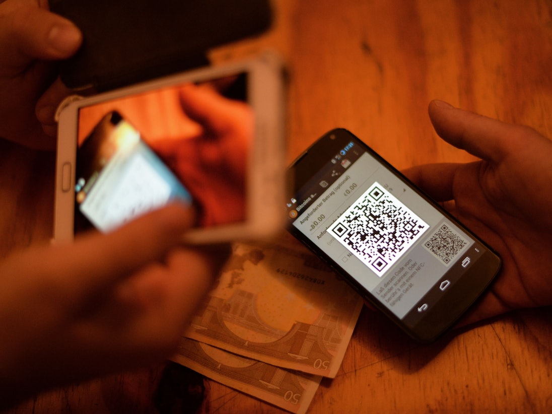 Zwei Personen verkaufen Bitcoin über ihre Smartphones.