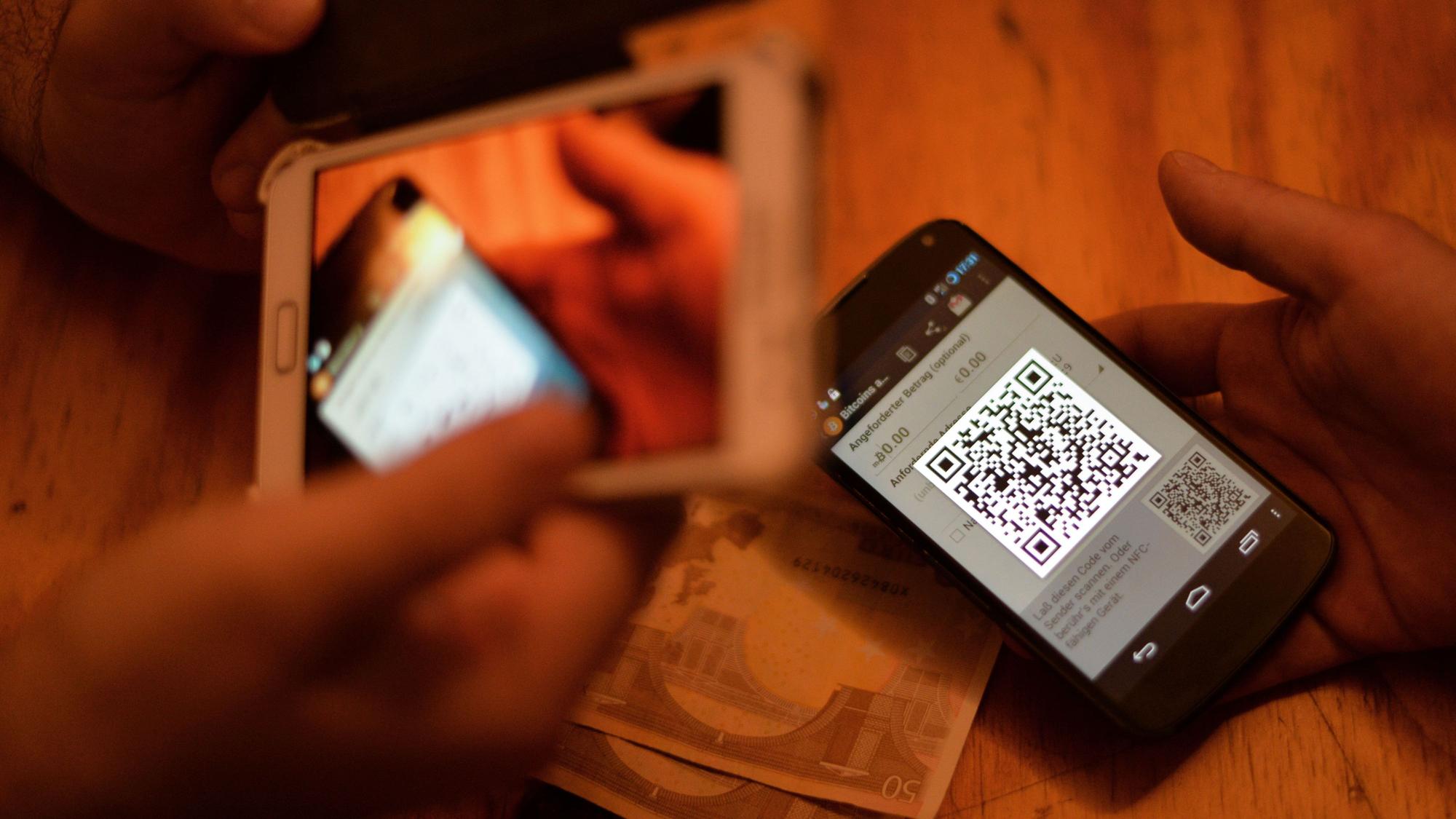 Zwei Personen verkaufen Bitcoin über ihre Smartphones.