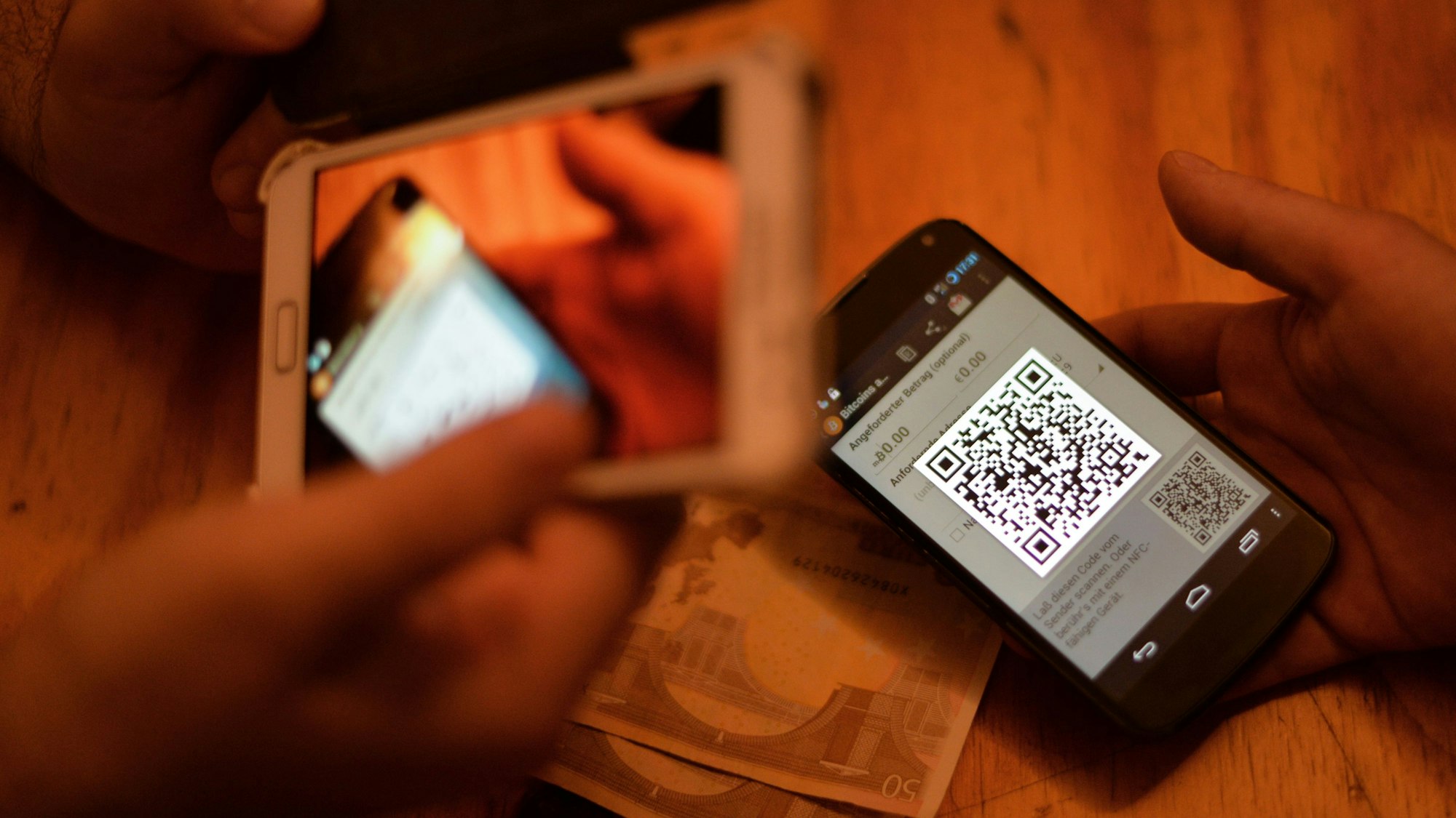 Zwei Personen verkaufen Bitcoin über ihre Smartphones.