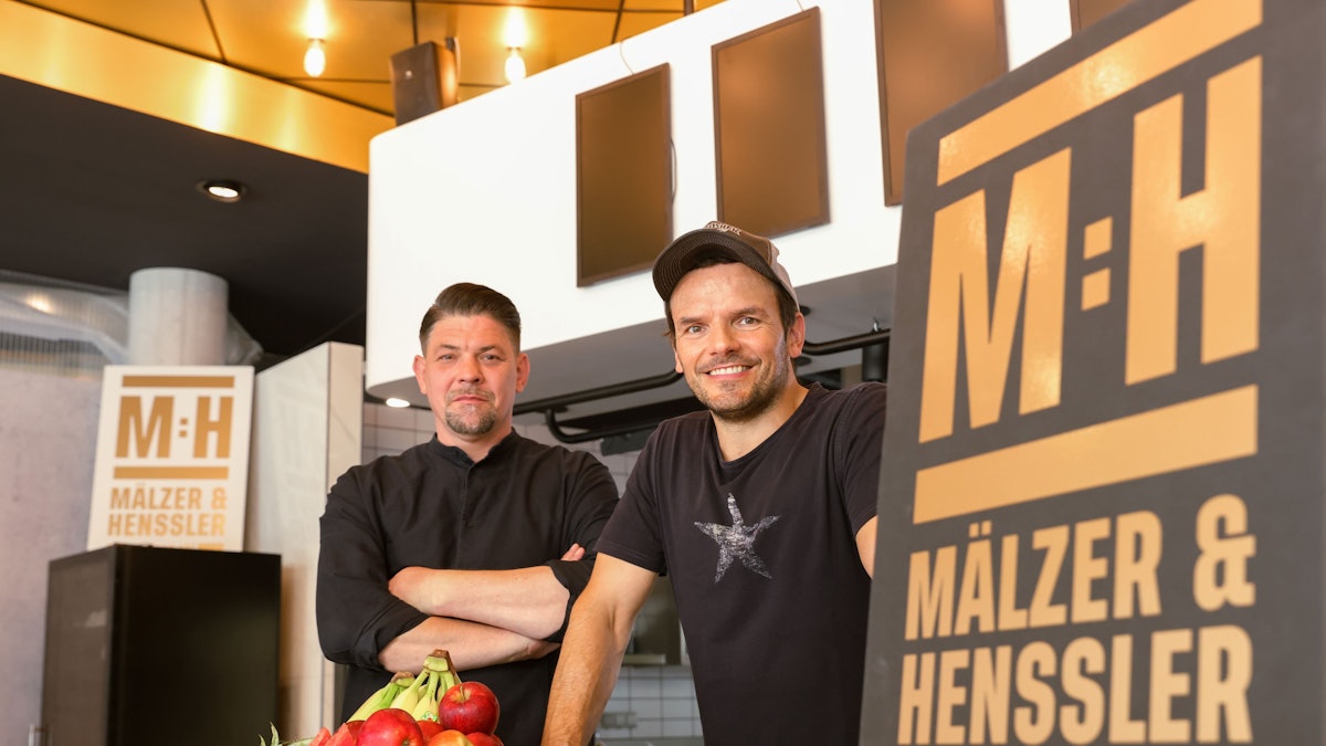 Tim Mälzer und Steffen Henssler stehen im Studio der neuen Kochshow „Mälzer und Henssler liefern ab!“ bei Vox