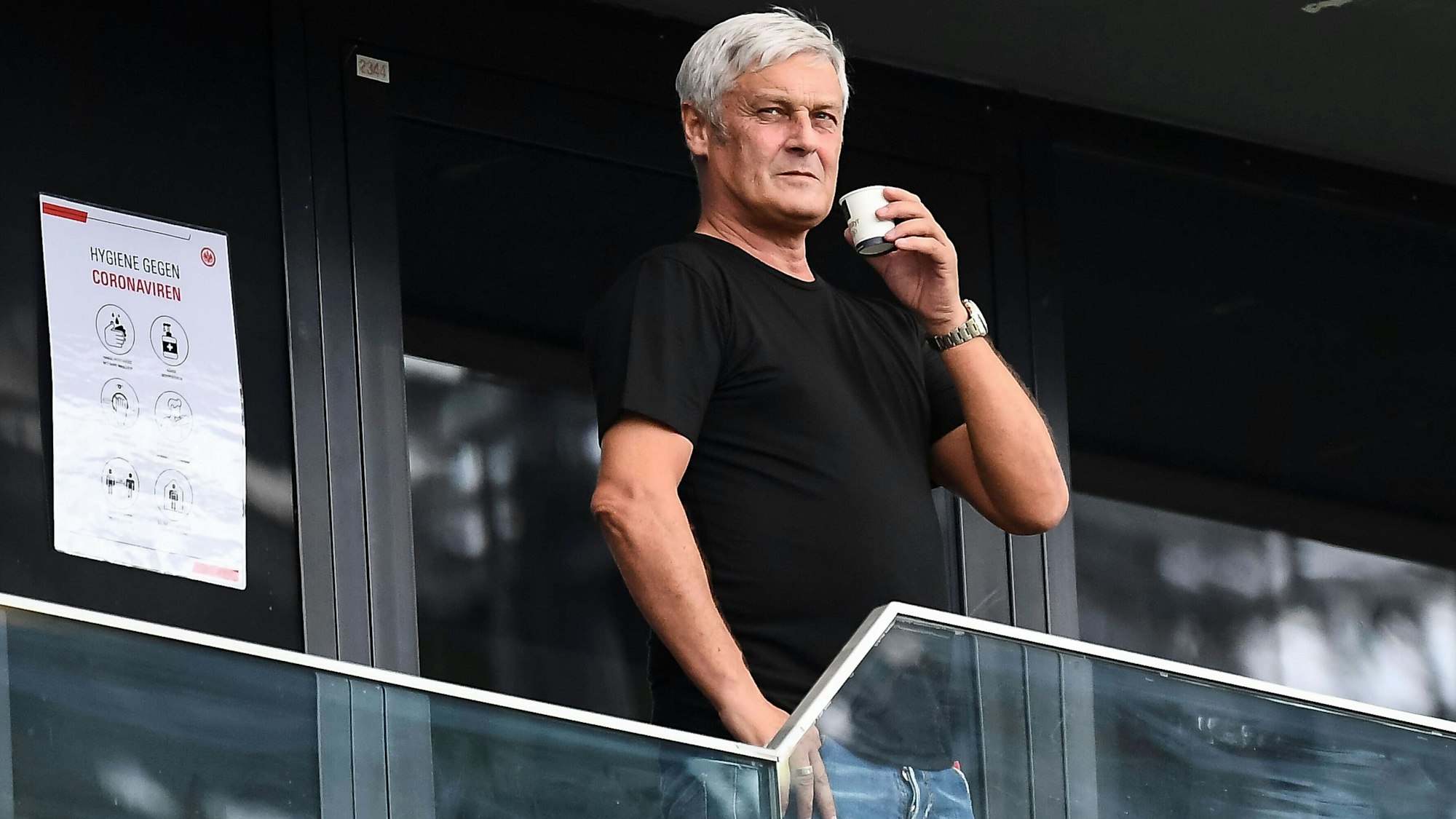 Armin Veh steht mit einer Tasse auf der Tribüne.