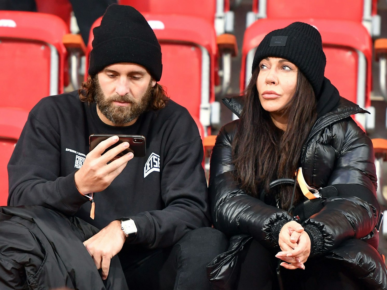 Silvio Heinevetter starrt auf sein Handy. Simone Thomalla sitzt neben ihm.