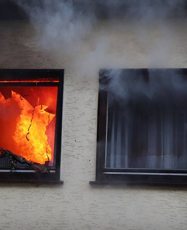 Hinter einem Fenster eines Hauses in Dortmund sind am 9. Januar 2019 Flammen zu sehen.