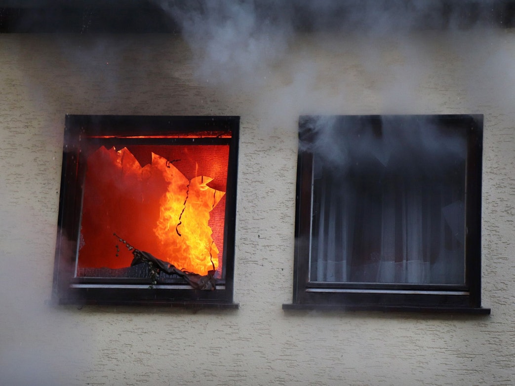 Hinter einem Fenster eines Hauses in Dortmund sind am 9. Januar 2019 Flammen zu sehen.