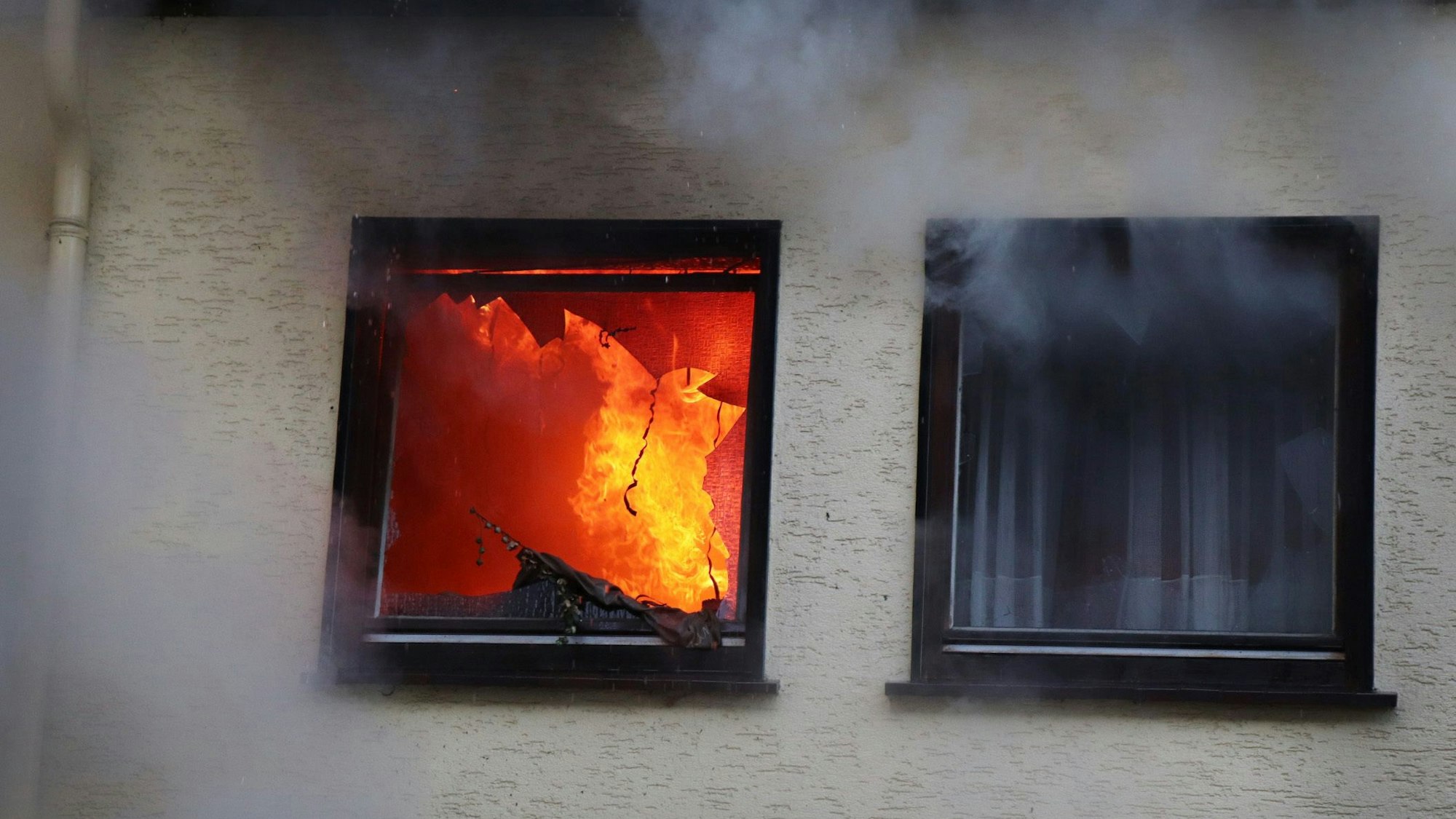 Hinter einem Fenster eines Hauses in Dortmund sind am 9. Januar 2019 Flammen zu sehen.