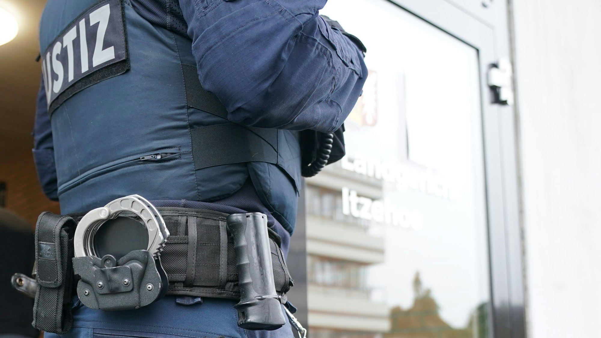 In Bayern wurde ein 14-jähriges Mädchen im Schlaf ermordet. Der Verdächtigte wurde festgenommen. Unser Symbolbild (aufgenommen am 19. Oktober 2021) zeigt einen Justizbeamten, der vor einem Eingang steht. Man sieht nur einen Teil von seinem Rücken.