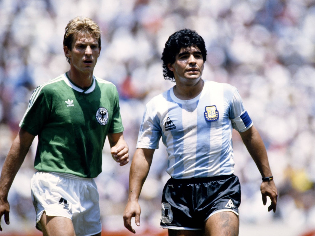 Links Karlheinz Förster im grünen Deutschland-Trikot, rechts Diego Armando Maradona in blau-weiß gestreiften Argentinien-Trikot.