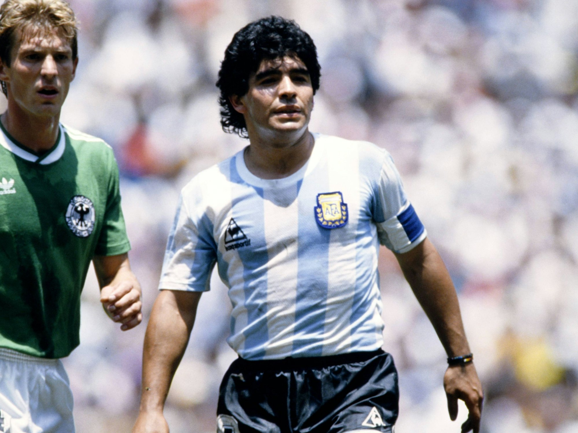 Links Karlheinz Förster im grünen Deutschland-Trikot, rechts Diego Armando Maradona in blau-weiß gestreiften Argentinien-Trikot.