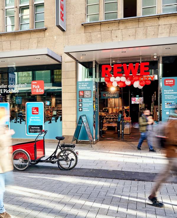 Menschen gehen am Rewe-Markt in der Zeppelinstraße in Köln vorbei.