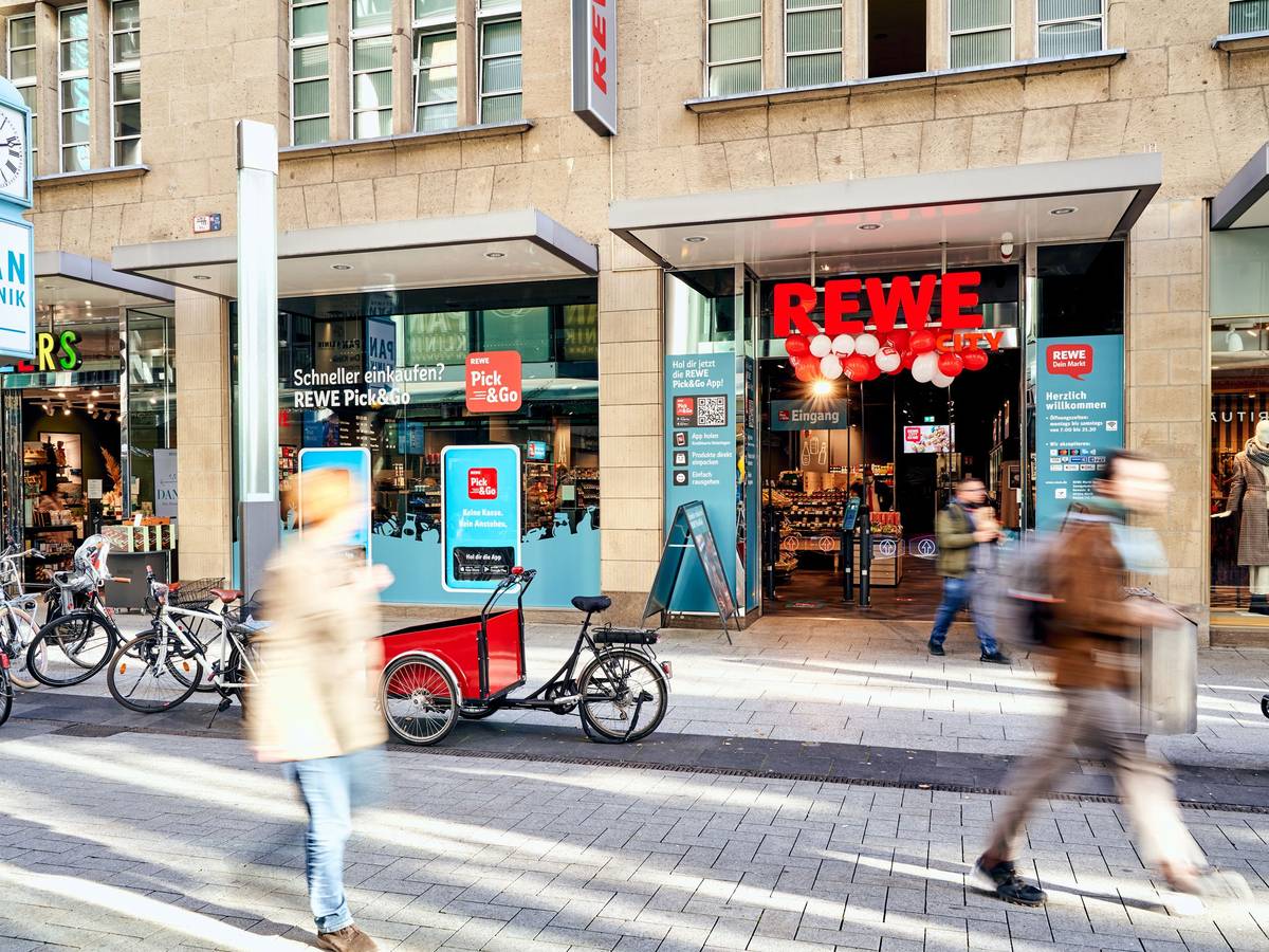 Menschen gehen am Rewe-Markt in der Zeppelinstraße in Köln vorbei.