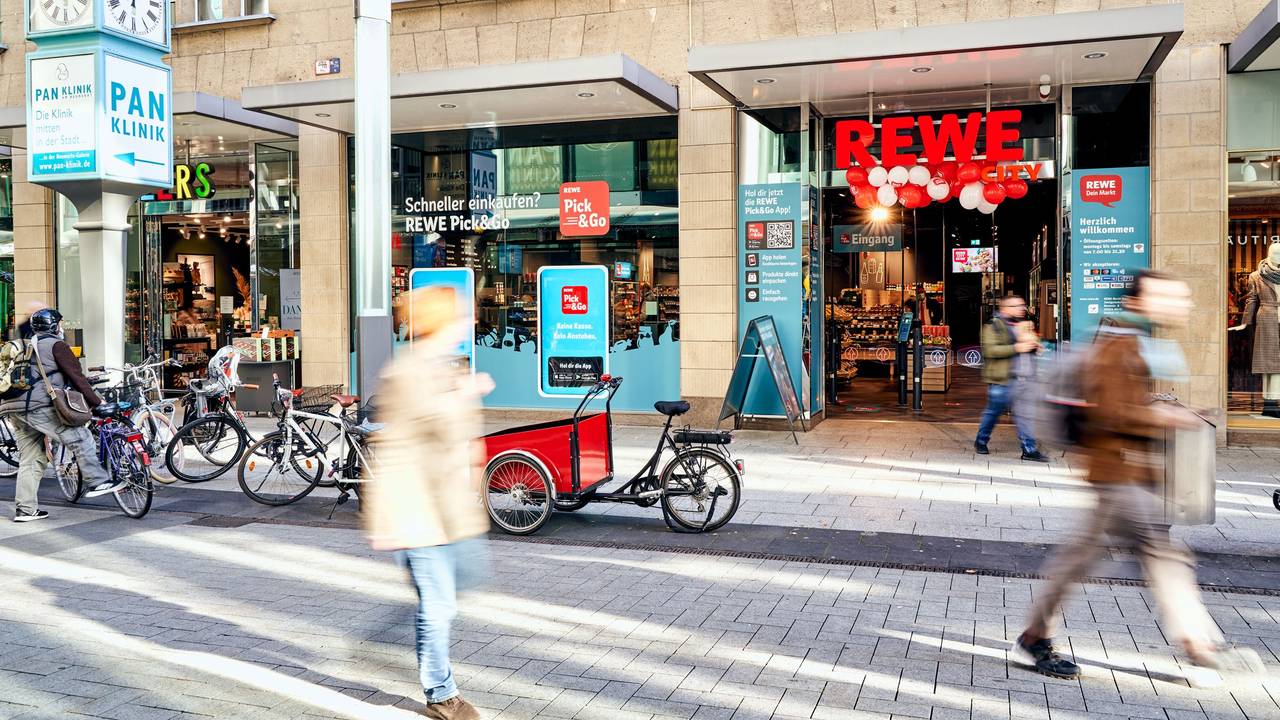 Menschen gehen am Rewe-Markt in der Zeppelinstraße in Köln vorbei.