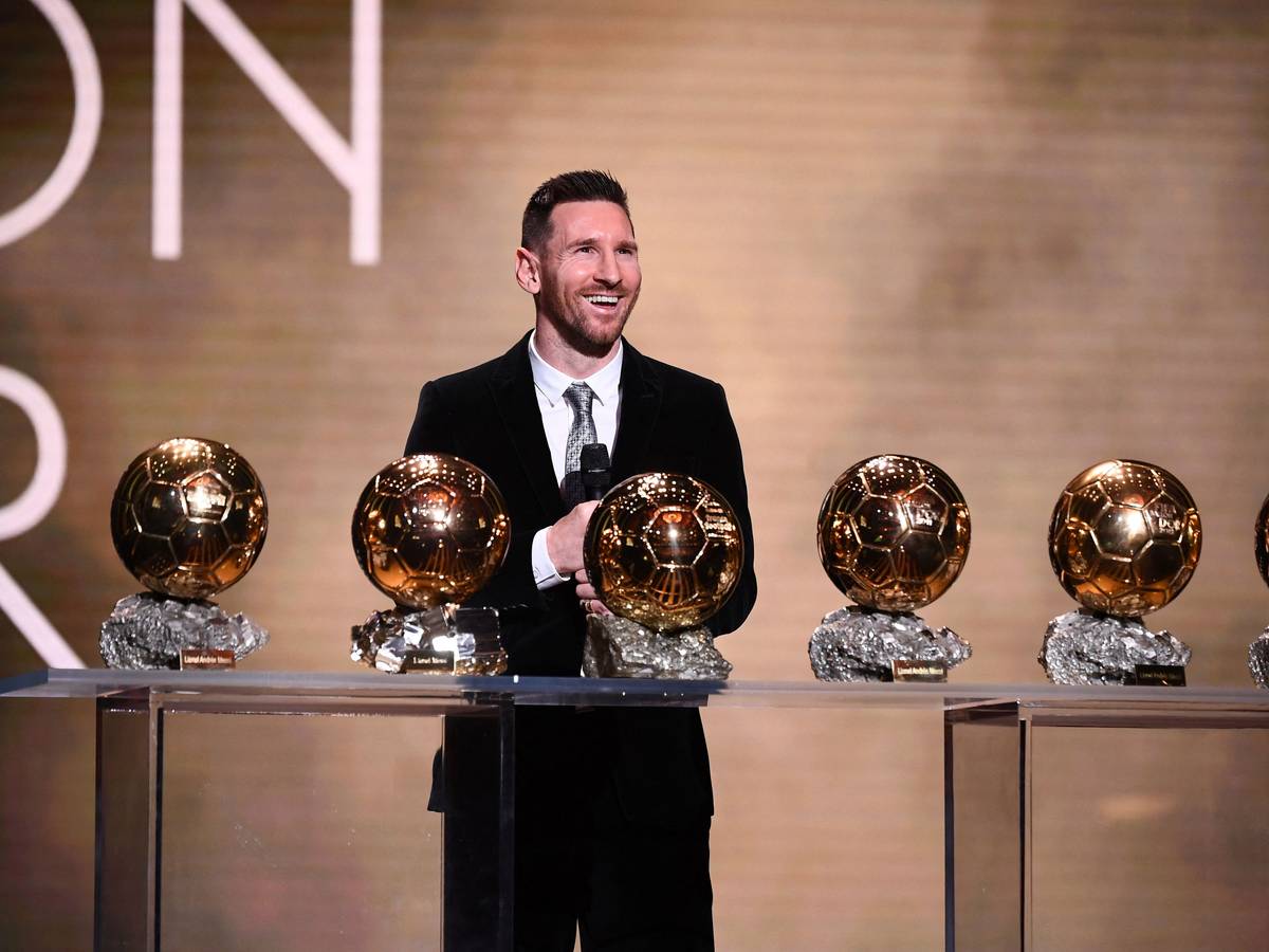 Lionel Messi steht vor einem Tisch mit dem sechsmal gewonnen Ballon d'Or.