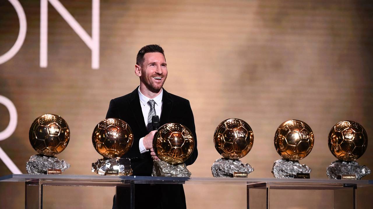 Lionel Messi steht vor einem Tisch mit dem sechsmal gewonnen Ballon d'Or.