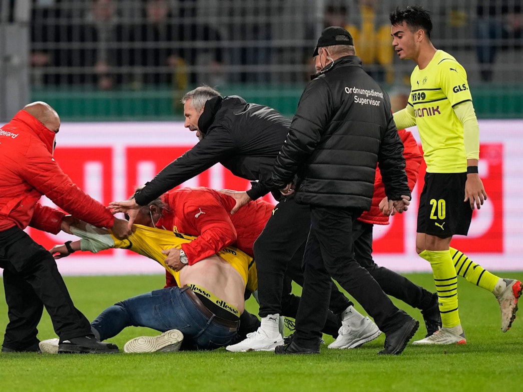 BVB-Trainer Marco Rose versucht zwischen den Ordnern und dem Flitzer zu schlichten.