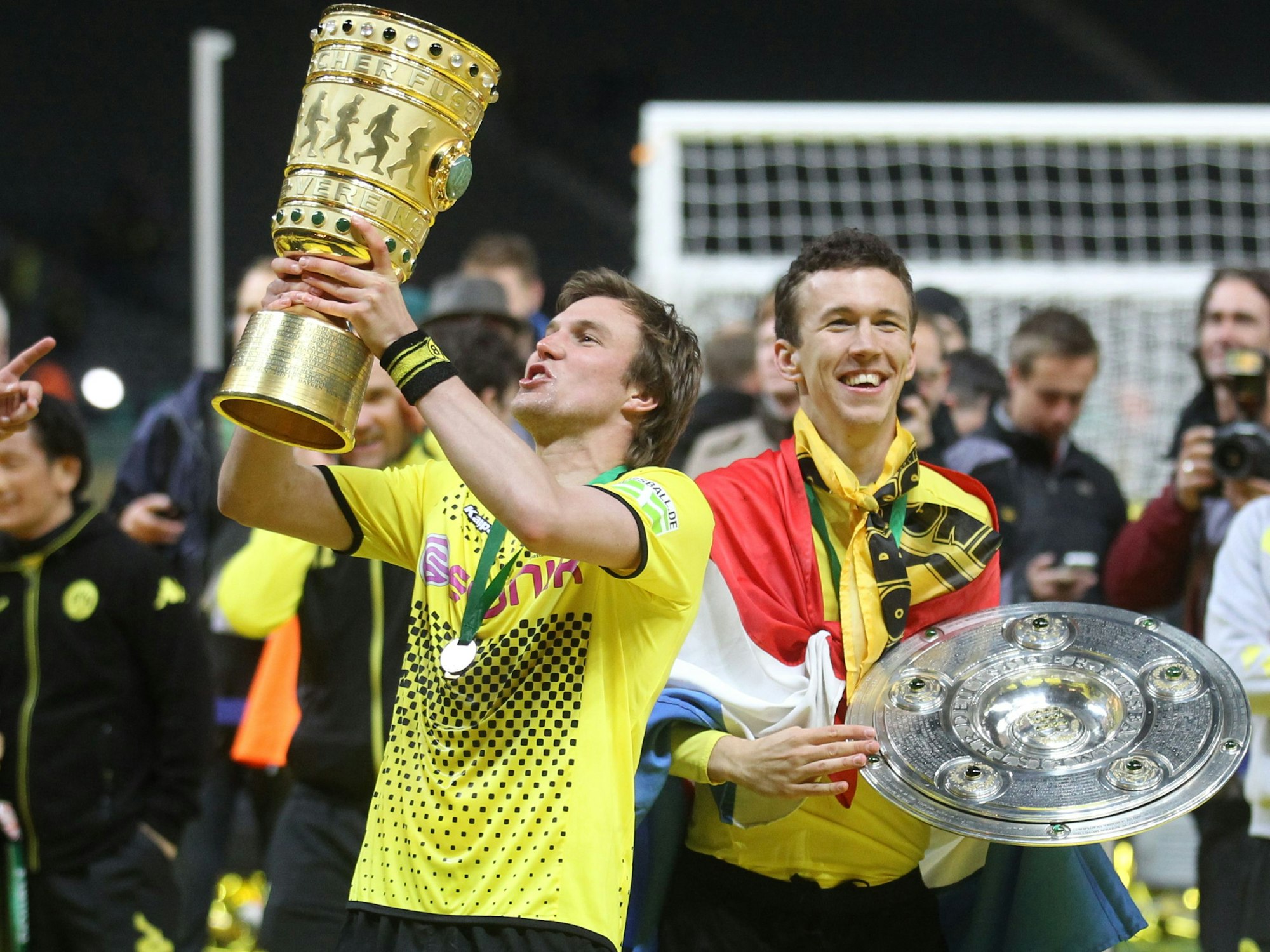 Damaliger Spieler Kevin Großkreutz von Borussia Dortmund jubelt am 12.05.2012 mit dem DFB-Pokal neben seinem Teamkollegen Ivan Perisic mit Meisterschale nach dem gewonnen DFB-Pokal-Finale zwischen Borussia Dortmund und Bayern München in Berlin.
