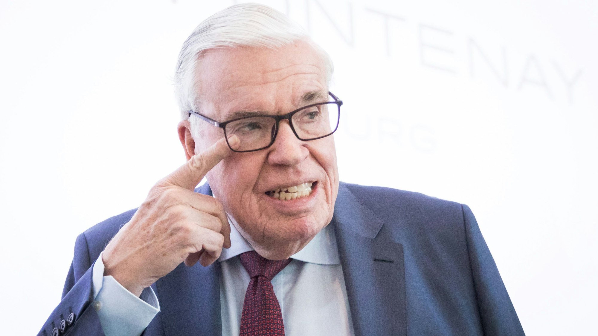 Klaus-Michael Kühne fasst sich mit dem Finger ans Auge.