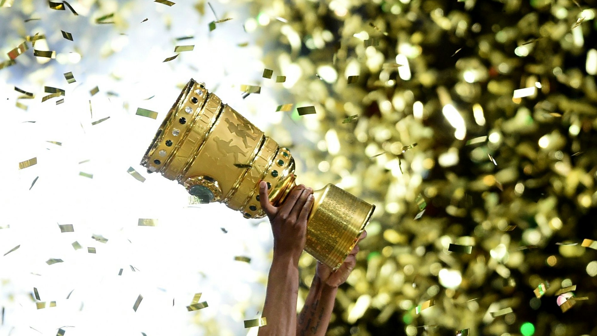Ein Wolfsburger hält den DFB-Pokal hoch.