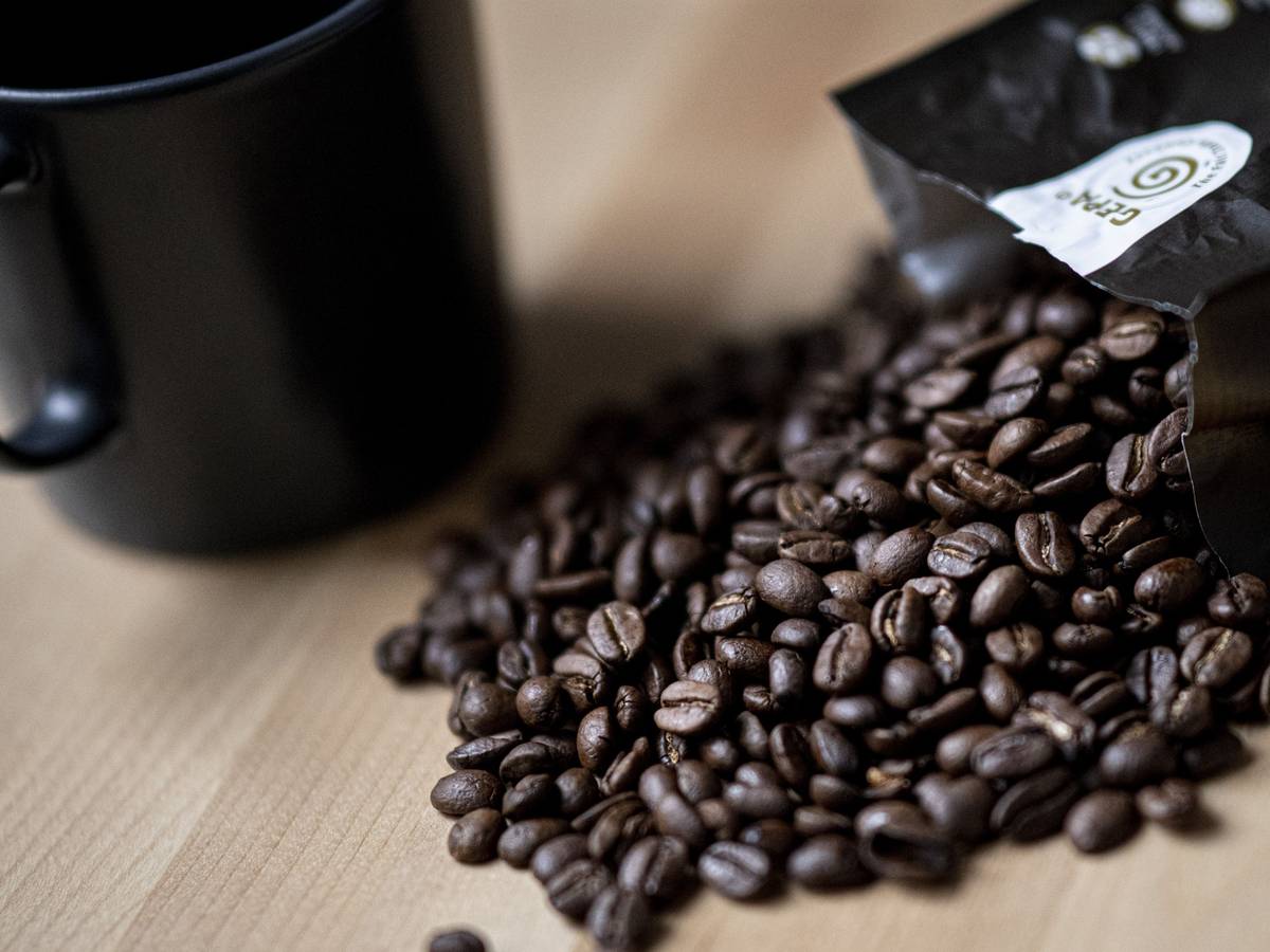 Guten Kaffee gibt es nicht überall. Doch woran erkennt man eigentlich guten Kaffee? Auf dem Symbolfoto (aufgenommen am 24. September 2021) liegen Kaffeebohnen neben einer Tasse auf einem Tisch.