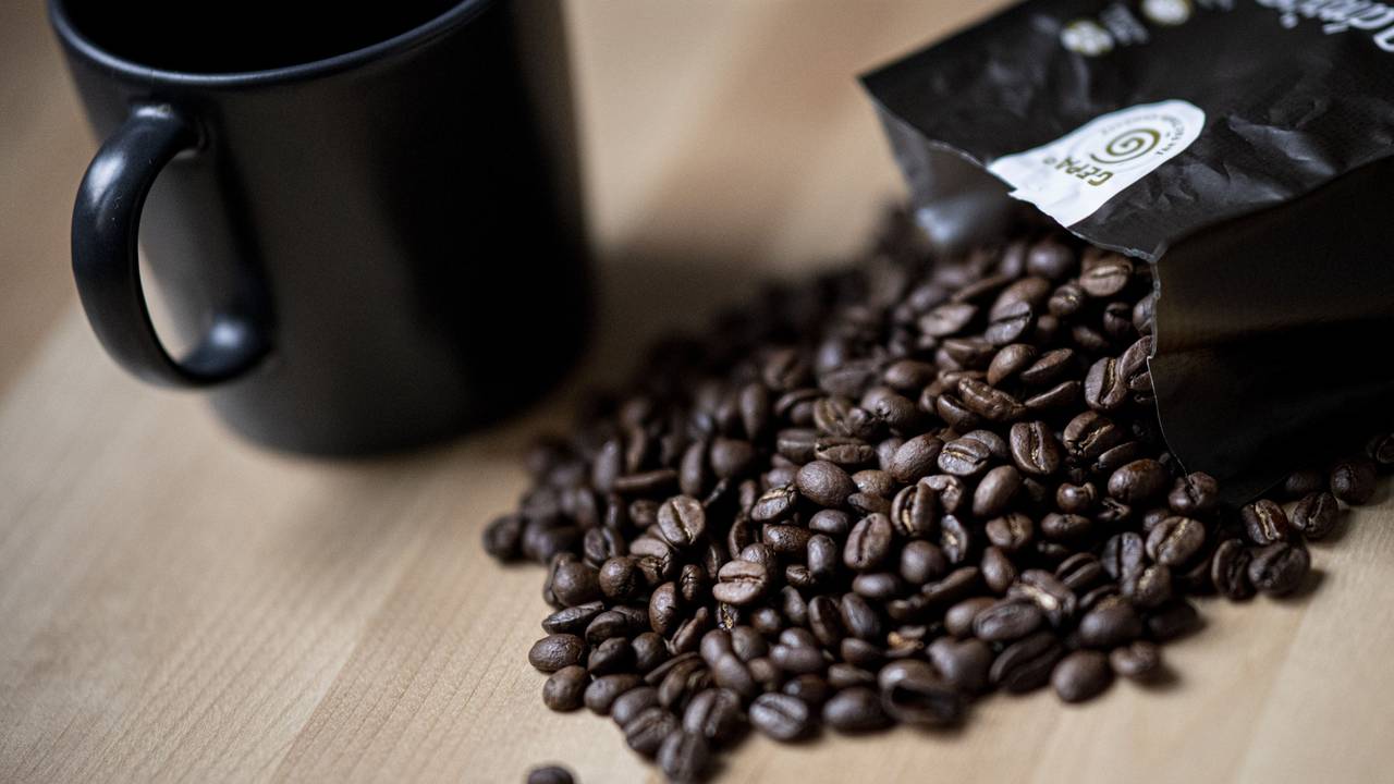 Guten Kaffee gibt es nicht überall. Doch woran erkennt man eigentlich guten Kaffee? Auf dem Symbolfoto (aufgenommen am 24. September 2021) liegen Kaffeebohnen neben einer Tasse auf einem Tisch.