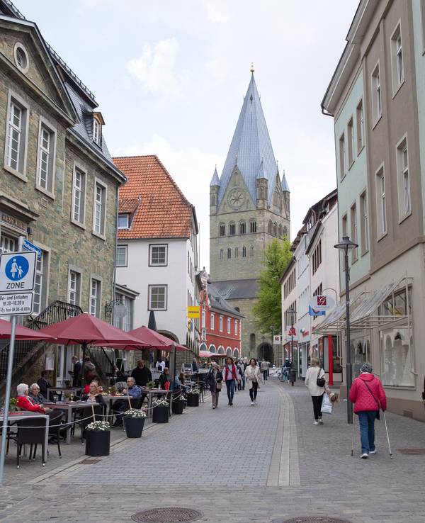 Gäste sitzen vor dem Ratskeller in Soest an der Rathausstraße. Im Hintergrund ist der St.Patrokli-Dom zu sehen.