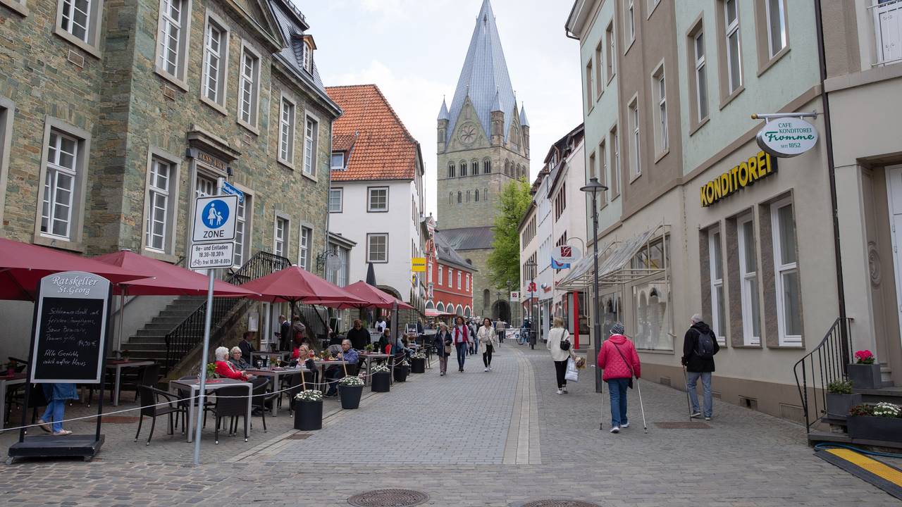 Gäste sitzen vor dem Ratskeller in Soest an der Rathausstraße. Im Hintergrund ist der St.Patrokli-Dom zu sehen.