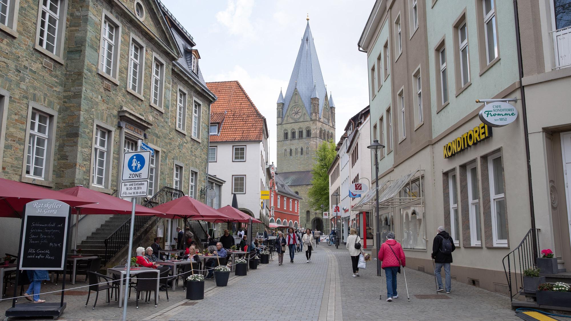 Gäste sitzen vor dem Ratskeller in Soest an der Rathausstraße. Im Hintergrund ist der St.Patrokli-Dom zu sehen.