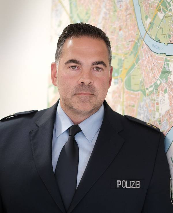 Michael Plagge blickt in die Kamera, hinter ihm der Stadtplan von Köln