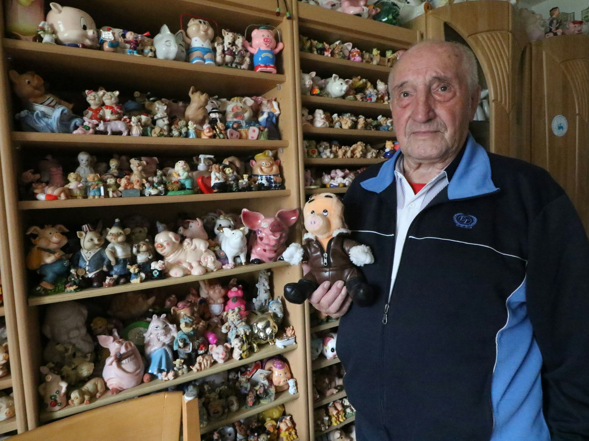 Rudolf Lausberg steht neben einem Regal voll mit Schweine-Figuren.