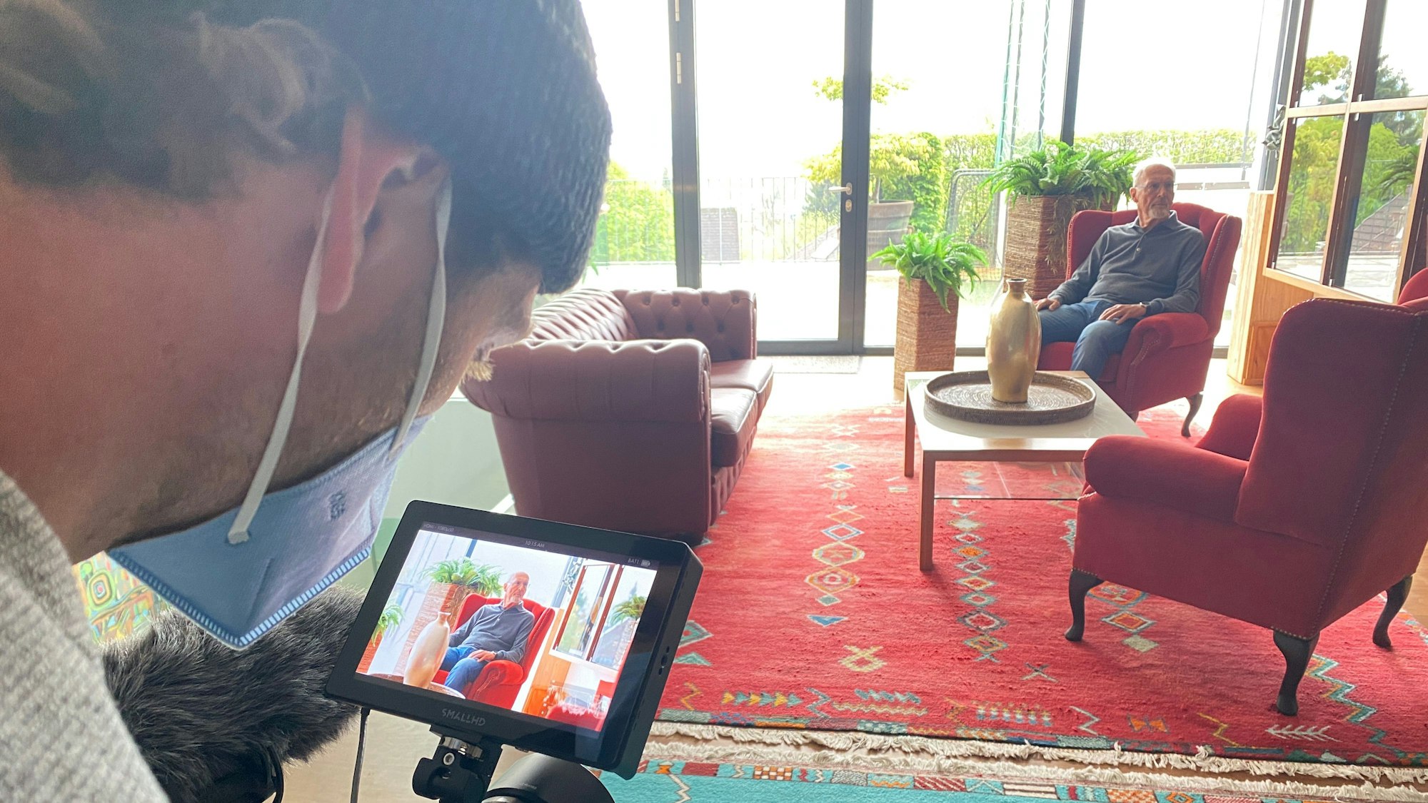 Franz Beckenbauer sitzt bei Dreharbeiten in einem Sessel.