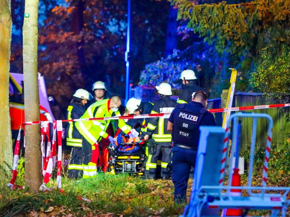 Sanitäter und Feuerwehrleute stehen an der Unfallstelle in Schildow, wo am Sonntagabend eine Fußgängergruppe von einem Auto erfasst wurde.