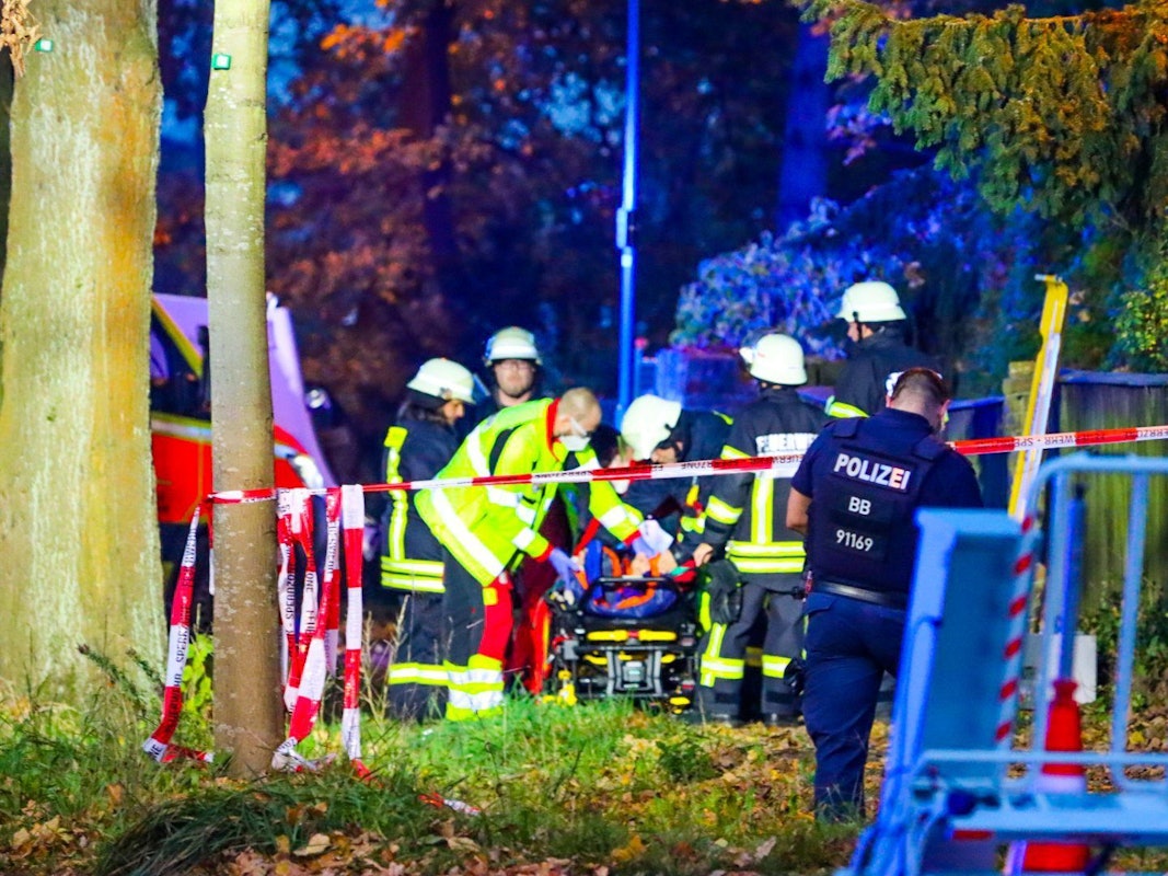 Sanitäter und Feuerwehrleute stehen an der Unfallstelle in Schildow, wo am Sonntagabend eine Fußgängergruppe von einem Auto erfasst wurde.