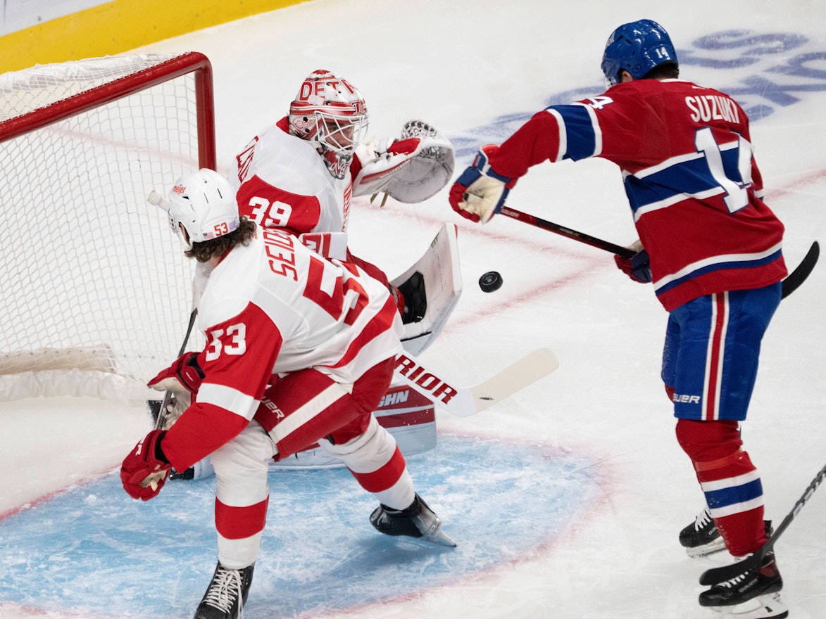 Nick Suzuki von Montreal schiebt den Puck ein, Detroits Goalie Alex Nedeljkovic sowie Moritz Seider können den Treffer nicht verhindern.