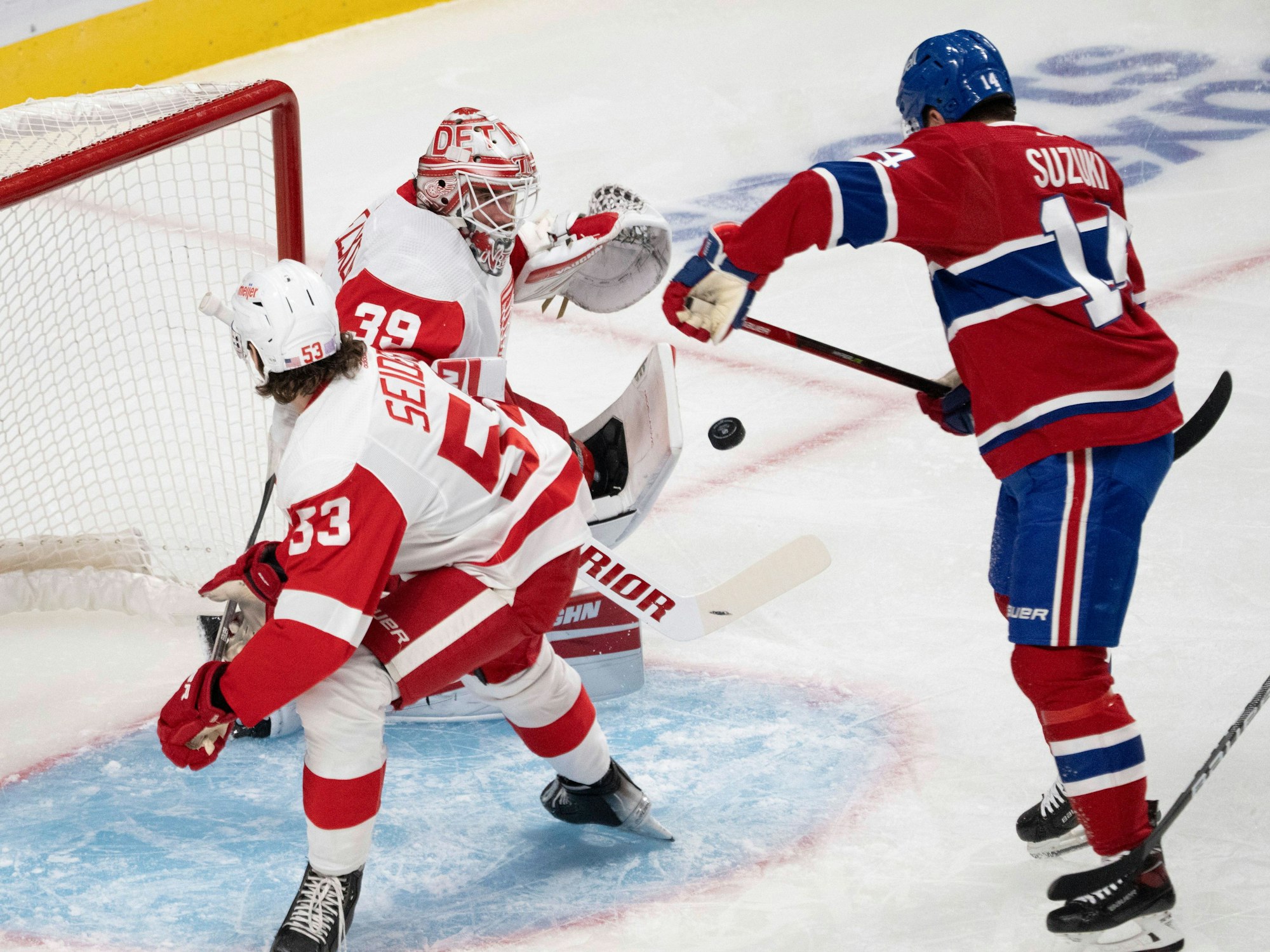 Nick Suzuki von Montreal schiebt den Puck ein, Detroits Goalie Alex Nedeljkovic sowie Moritz Seider können den Treffer nicht verhindern.