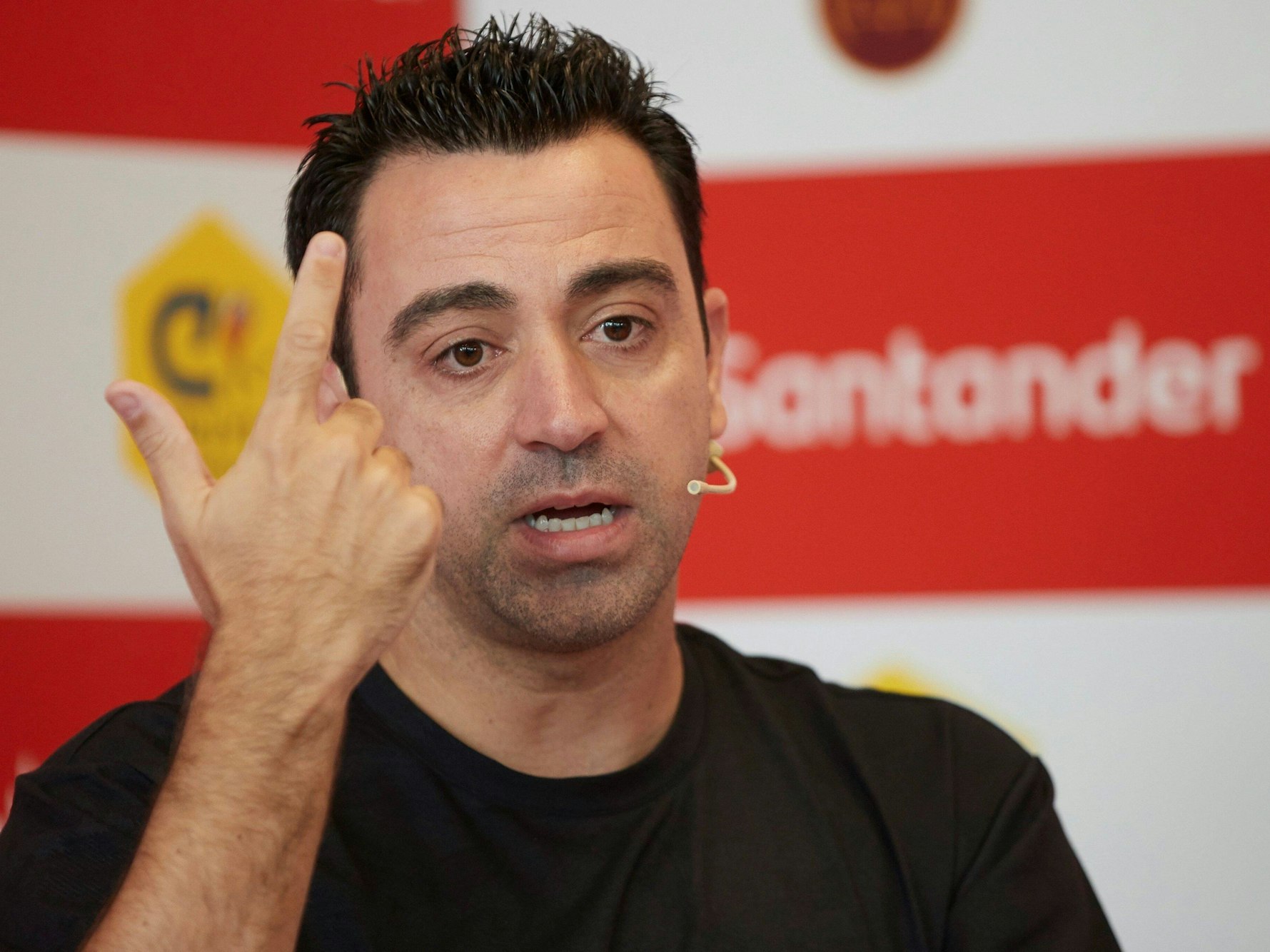 Bei der Pressekonferenz hebt Xavi den Zeigefinger.