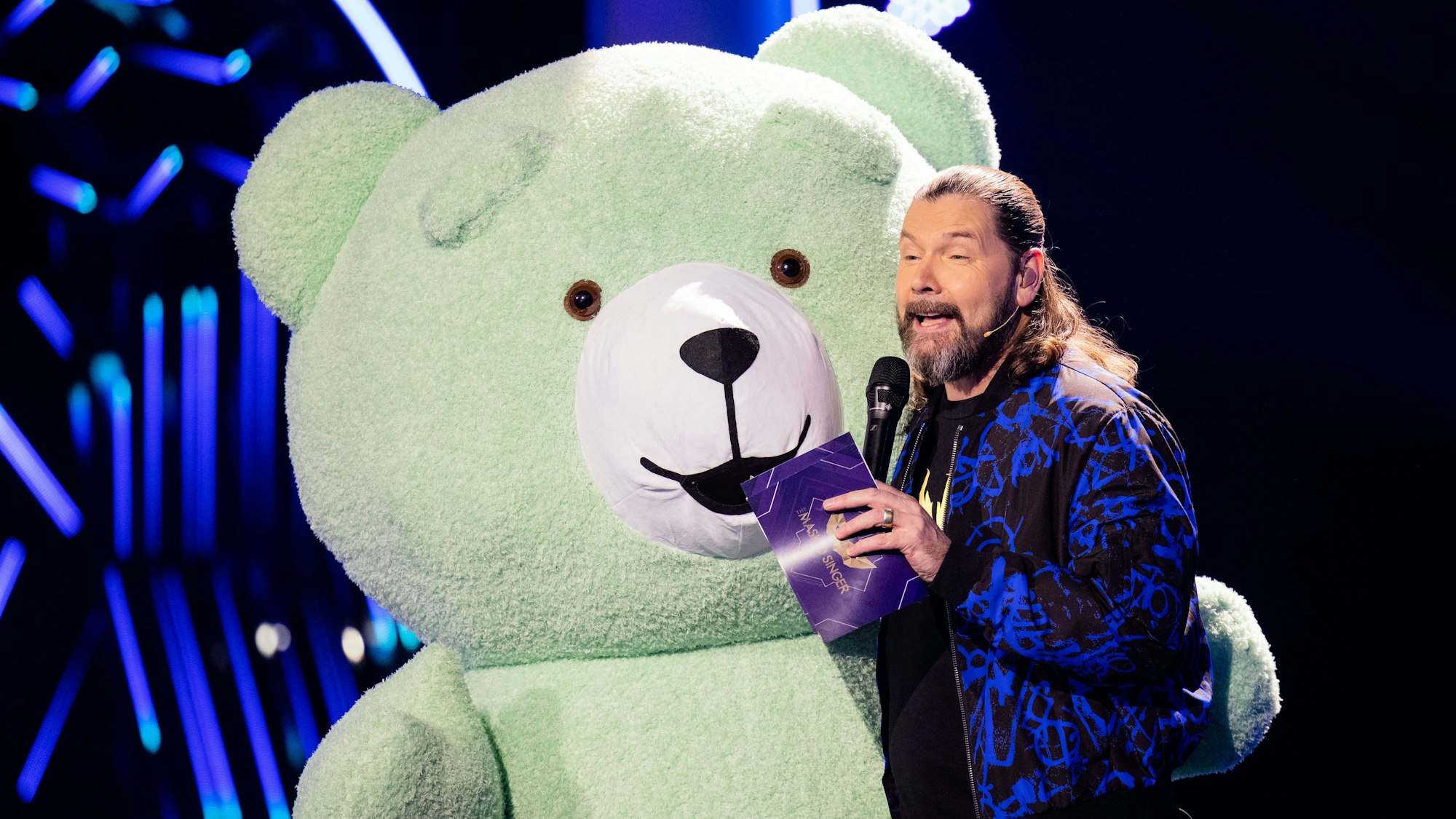 ProSieben wird im ersten Halbjahr 2022 die neue Show „The Masked Dancer“ ausstrahlen. Auf dem Foto (aufgenommen am 30. Oktober 2021) sieht man Ray Garvey aus dem Rateteam der Prosieben-Show "The Masked Singer". Neben ihm steht ein Teddy.