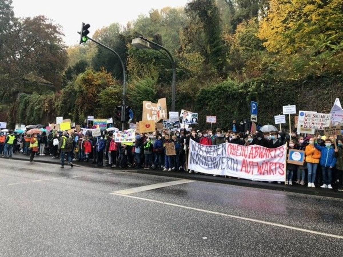 Schülerinnen und Schüler des Gymnasiums Nonnenwerth stehen an einer Straße und demonstrieren für den Erhalt ihrer Schule.