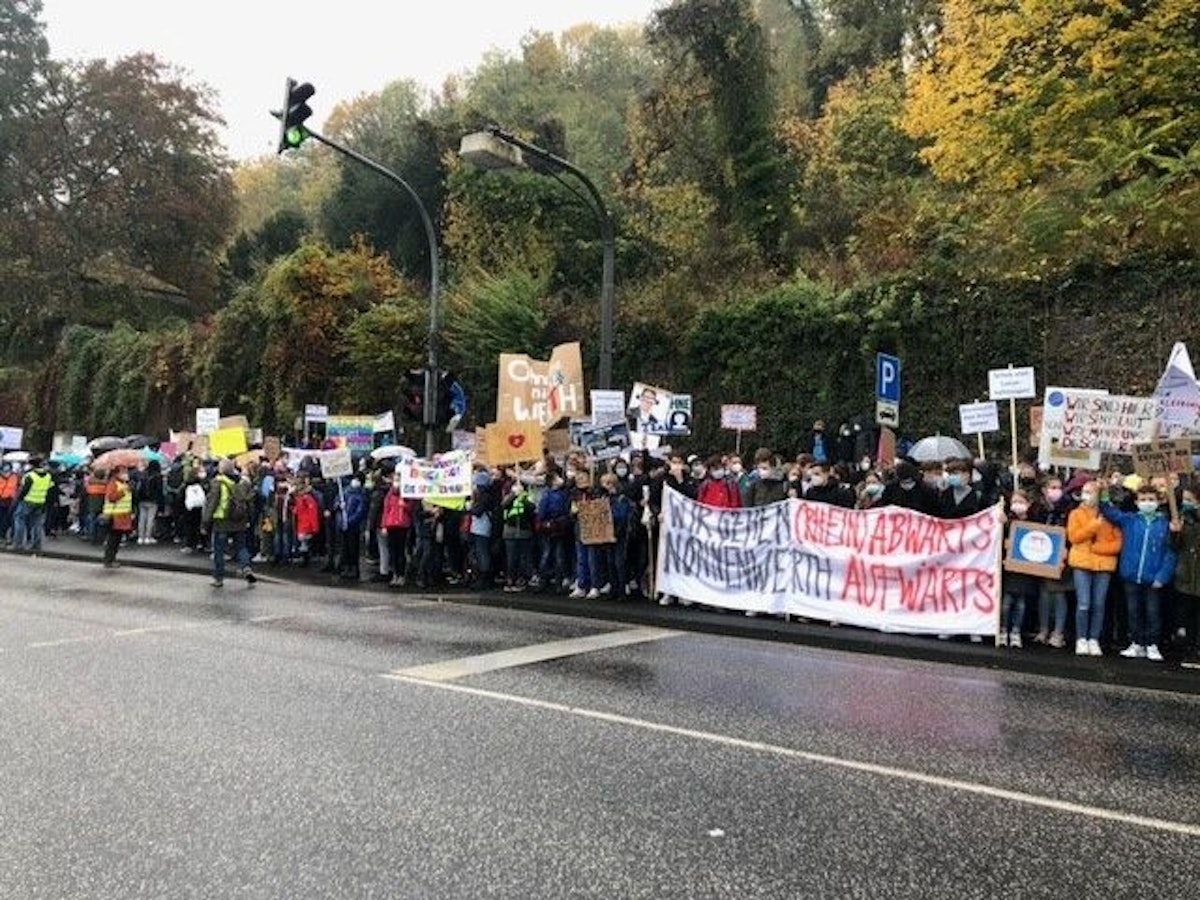 Schülerinnen und Schüler des Gymnasiums Nonnenwerth stehen an einer Straße und demonstrieren für den Erhalt ihrer Schule.