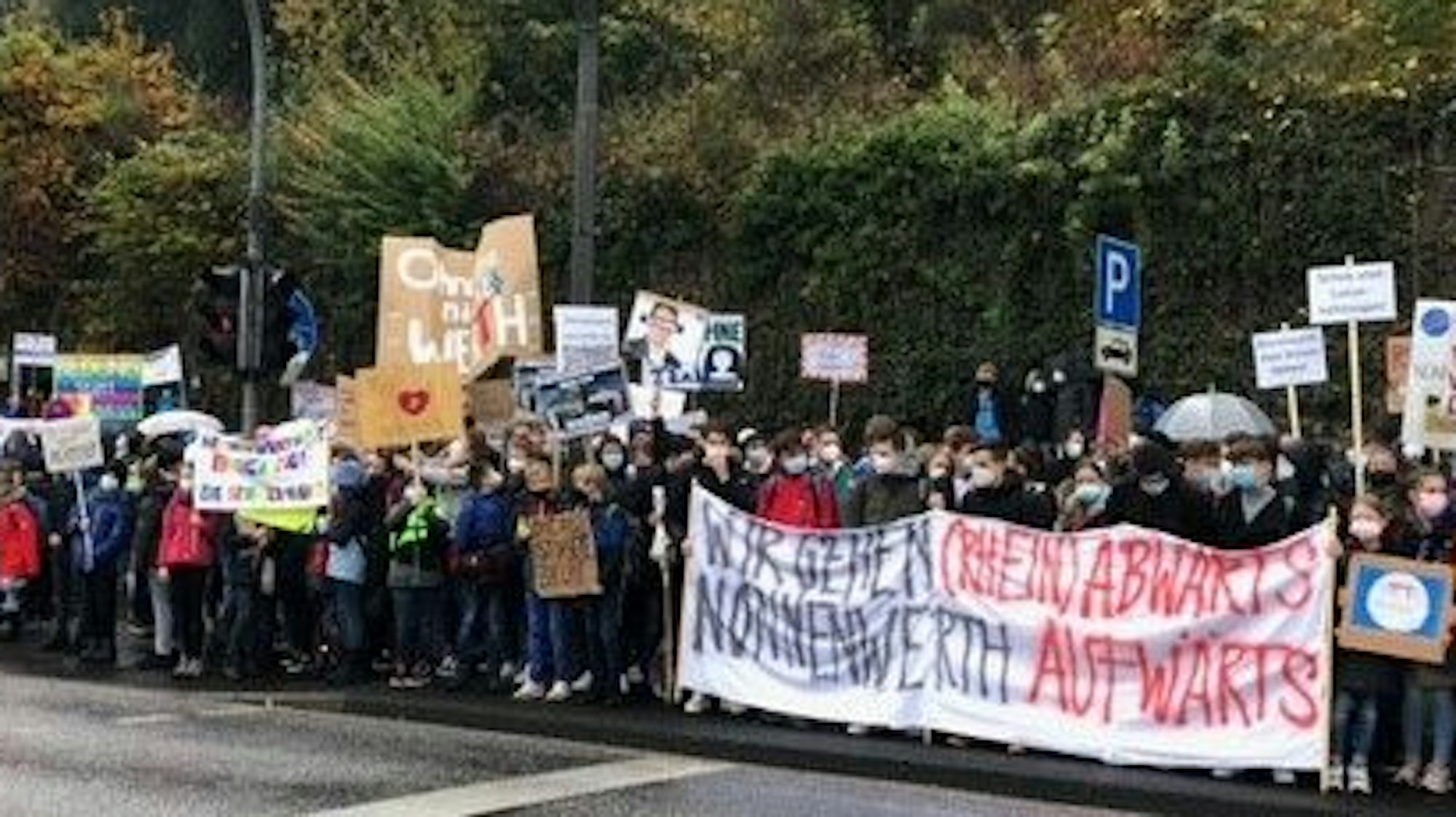 Schülerinnen und Schüler des Gymnasiums Nonnenwerth stehen an einer Straße und demonstrieren für den Erhalt ihrer Schule.