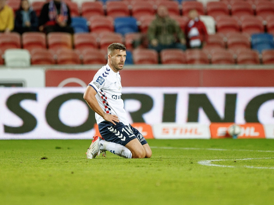 Lukas Podolski kniet auf dem Platz.