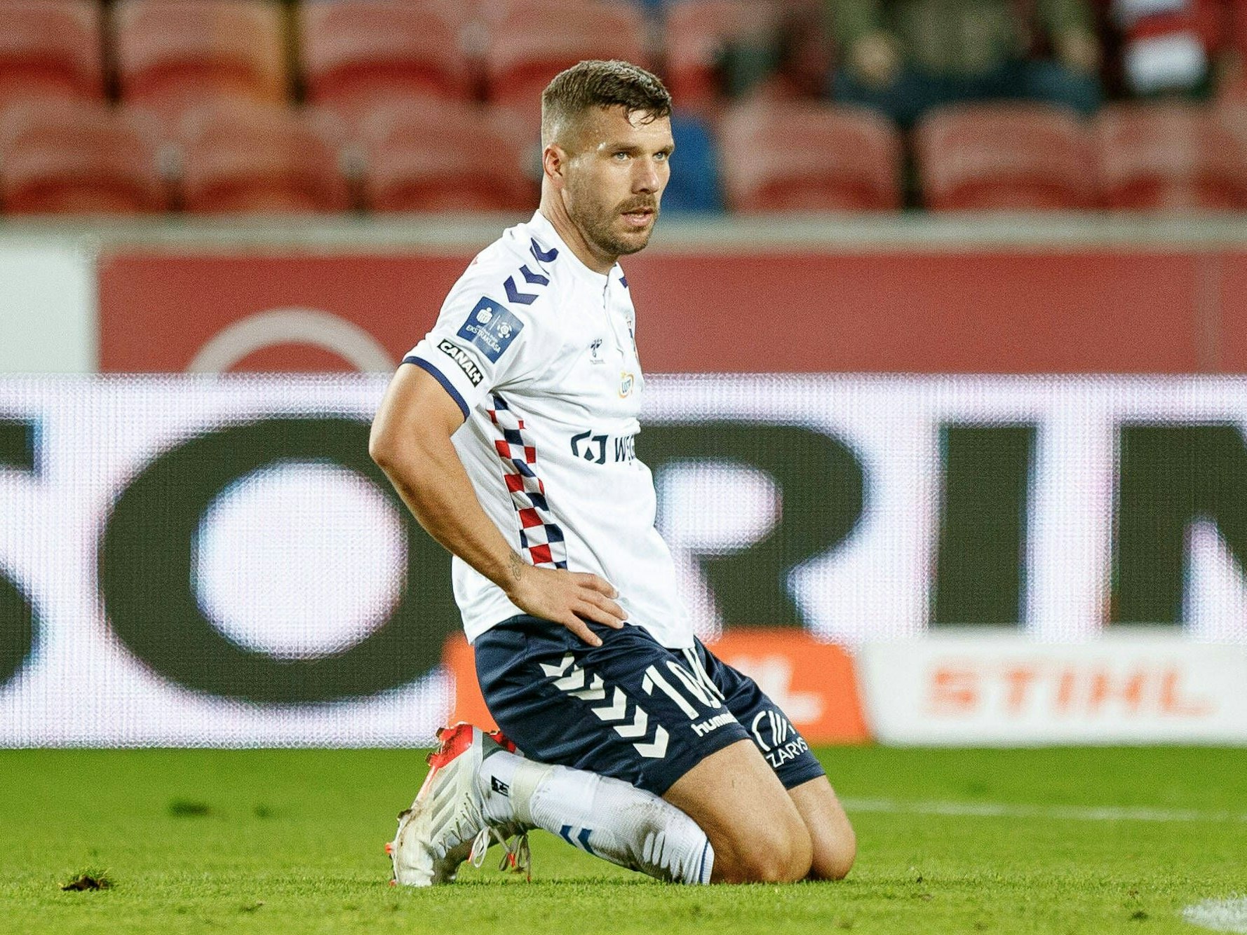 Lukas Podolski kniet auf dem Platz.