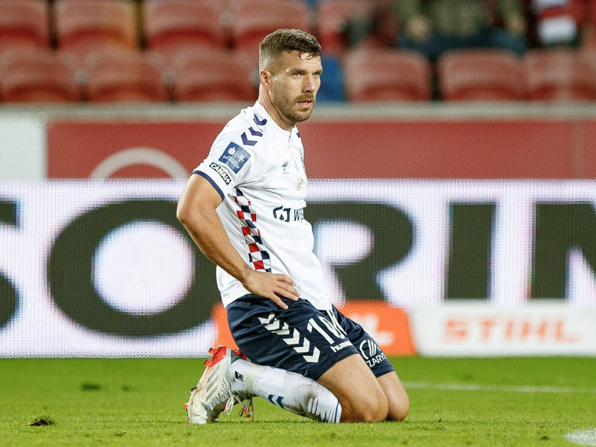 Lukas Podolski kniet auf dem Platz.
